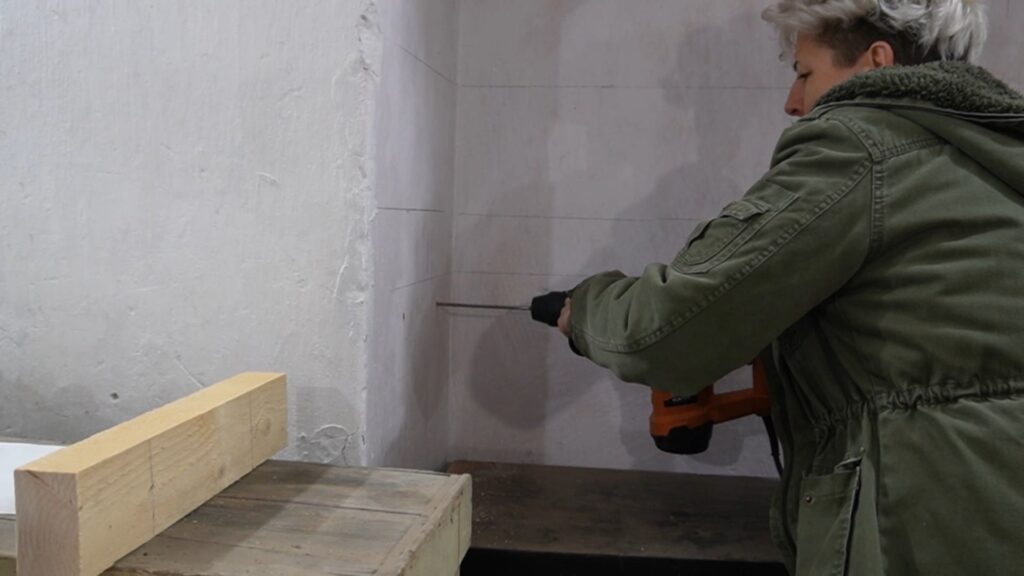 Bušenje zida udarnom bušilicom za postavljanje nosača police.