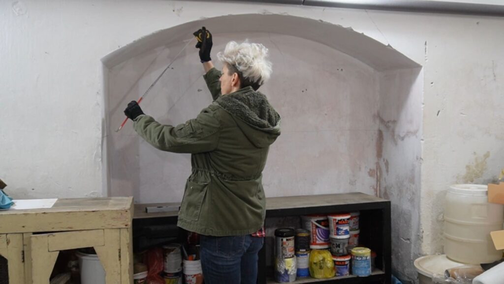 Merenje dimenzija niše iznad komode pre izrade police za odlaganje farbi i alata.