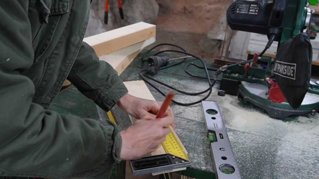 Obeležavanje mesta za bušenje na drvenim nosačima police pre montaže.