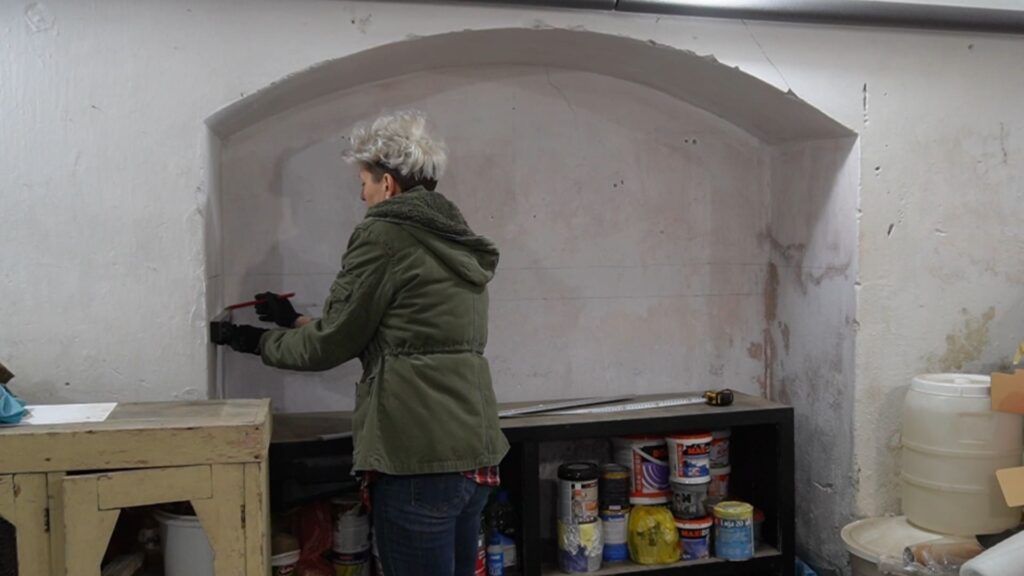 Obeležavanje linije na zidu za pravilno postavljanje police iznad komode.