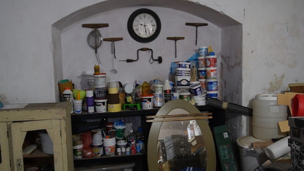 Komoda i niša pre sređivanja sa neorganizovanim bojama i materijalom.