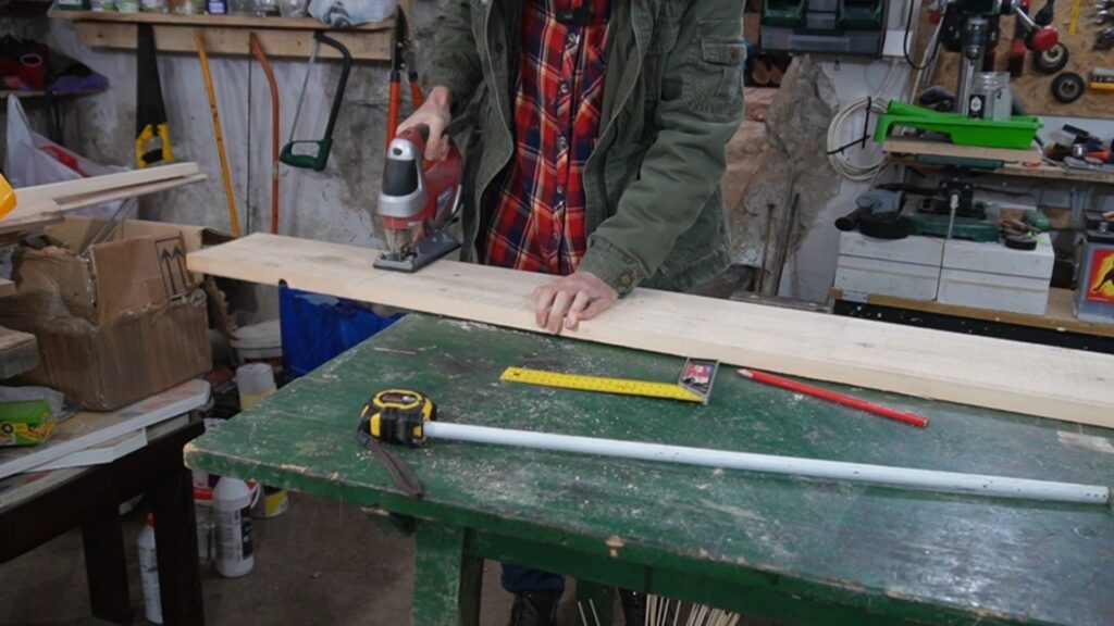 Sečenje drvene daske ubodnom testerom za izradu police u radionici.