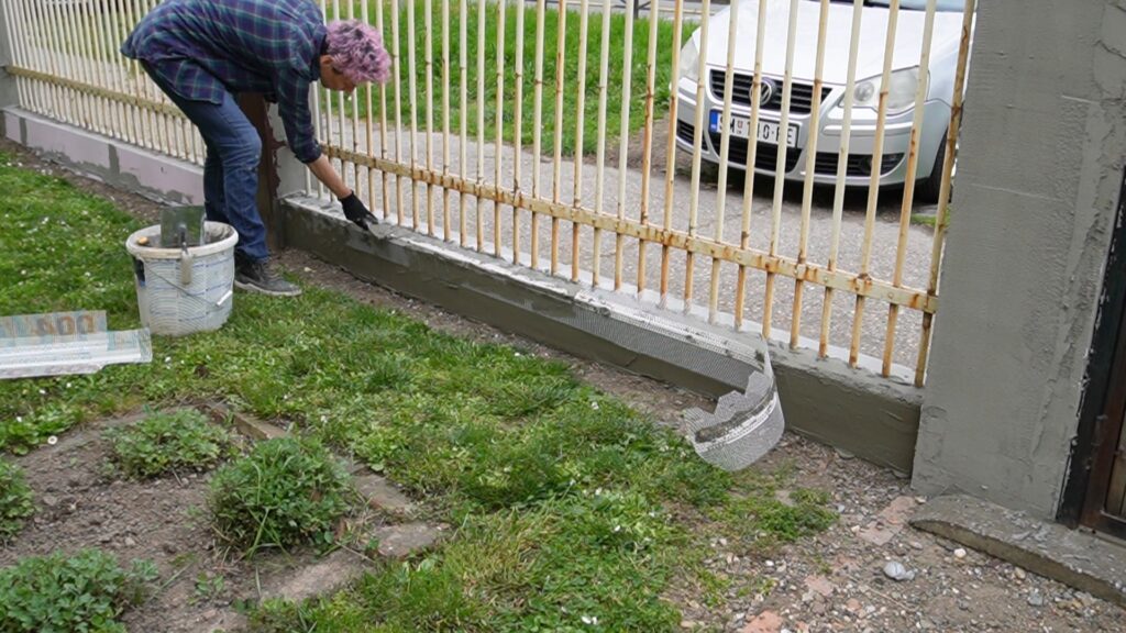 Obrađivanje temelja ograde pre popravke oštećenja i završnog krečenja
