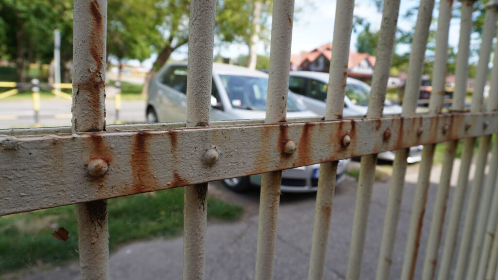 Rđa i oštećena stara boja na metalnoj ogradi