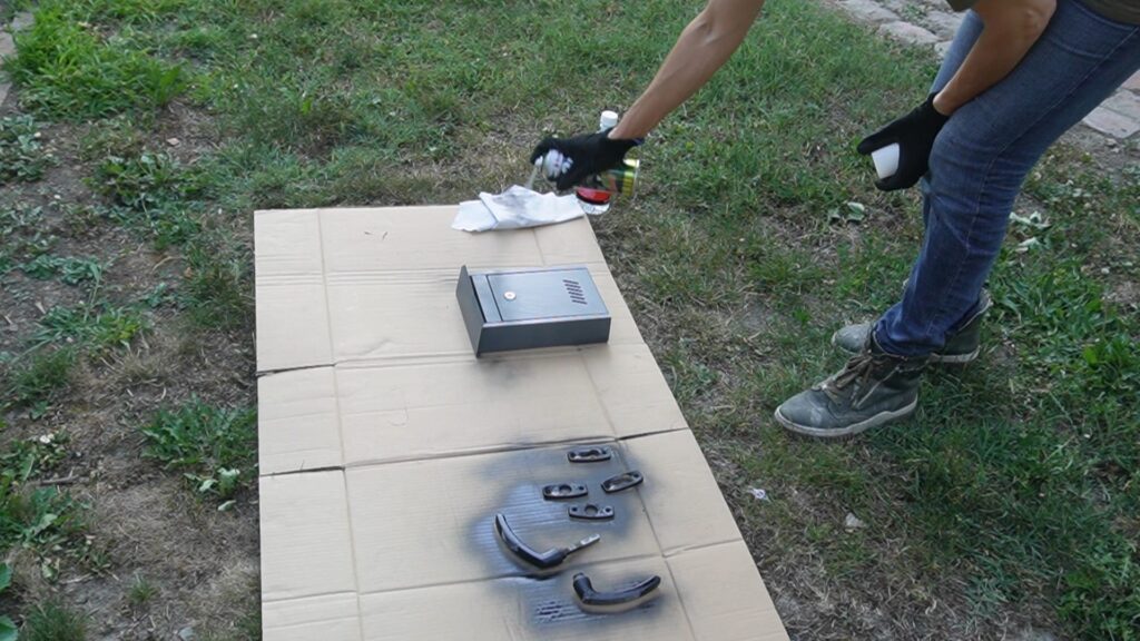 Farbanje poštanskog sandučeta crnom bojom za metal u spreju radi uklapanja sa ogradom