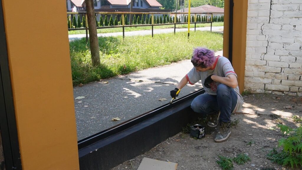 Nanošenje boje za metal na unutrašnju stranu metalnog okvira ograde pre montaže drvenih panela