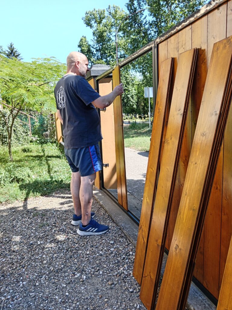 Metalni okvir ograde delimično popunjen novim drvenim panelima od brodskog poda