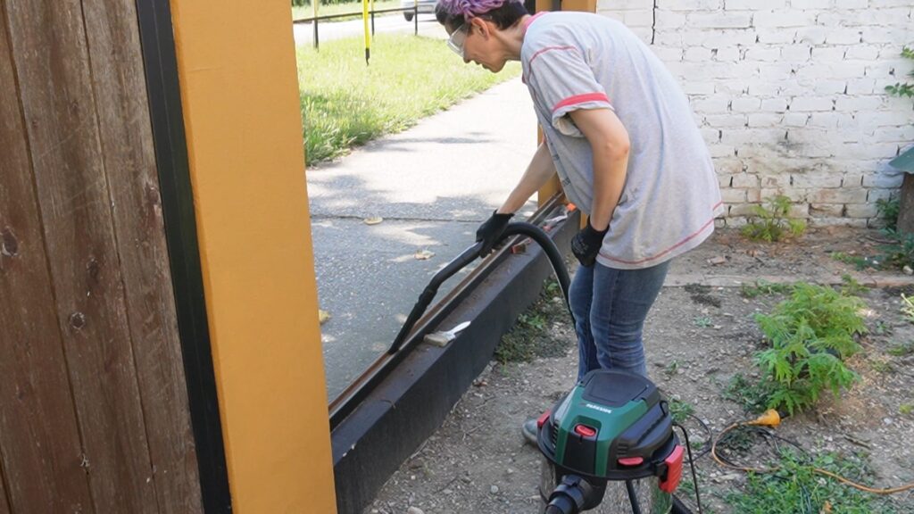 Usisavanje prašine i nečistoća iz donjeg dela metalnog okvira ograde pre farbanja
